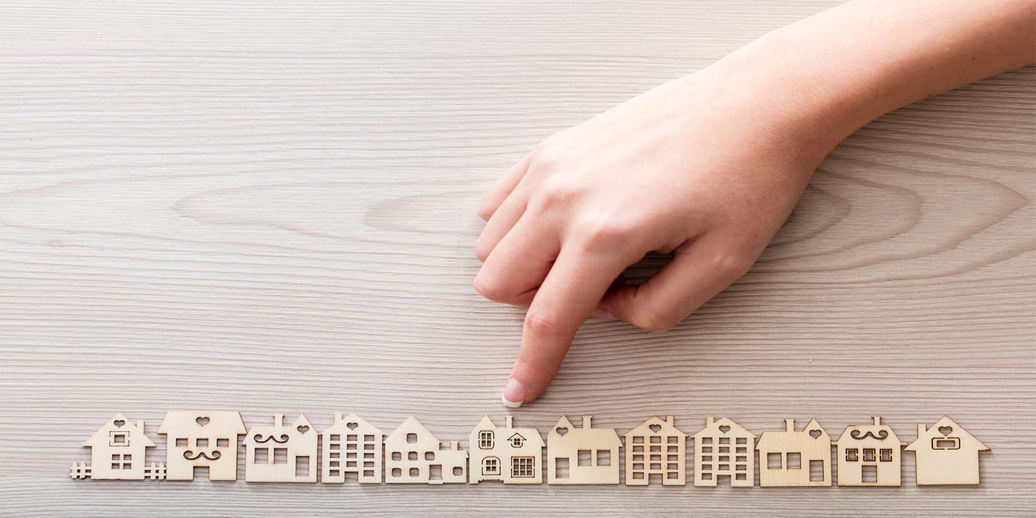 Finger pointing at house to fix and flip as investment